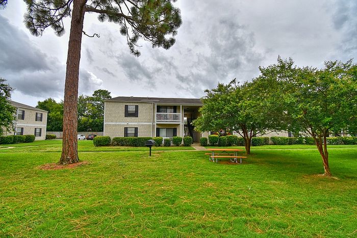 Charming apartment complex nestled in lush green surroundings with outdoor seating, showcasing tranquility and community living.