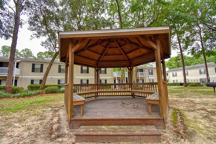 Charming outdoor gazebo in a serene apartment complex, surrounded by lush greenery and inviting walkways.