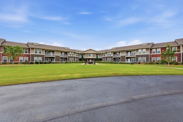 Spacious suburban apartment complex with charming architecture and lush green lawns under a clear blue sky.