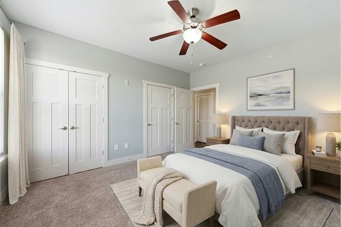 Elegant bedroom with plush carpet, stylish ceiling fan, and inviting bed arrangement, exuding comfort and tranquility.