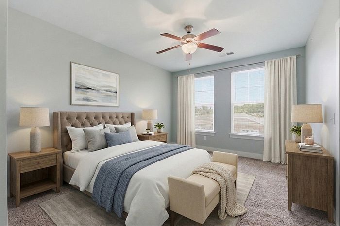 Elegant bedroom with plush bed, stylish decor, and ample natural light through large windows, offering a tranquil retreat.