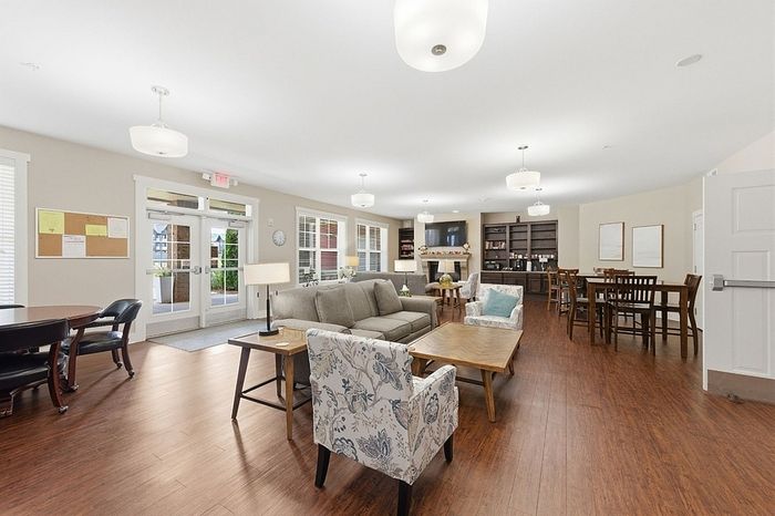Elegant and spacious communal living area featuring stylish armchairs, a cozy sofa, modern wooden floors, and abundant natural light.