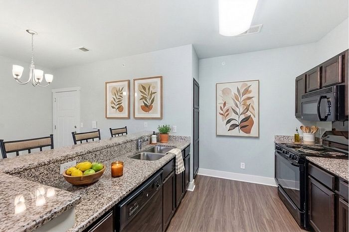 Elegant kitchen with granite countertops, modern appliances, and chic bar seating complemented by tasteful botanical art.