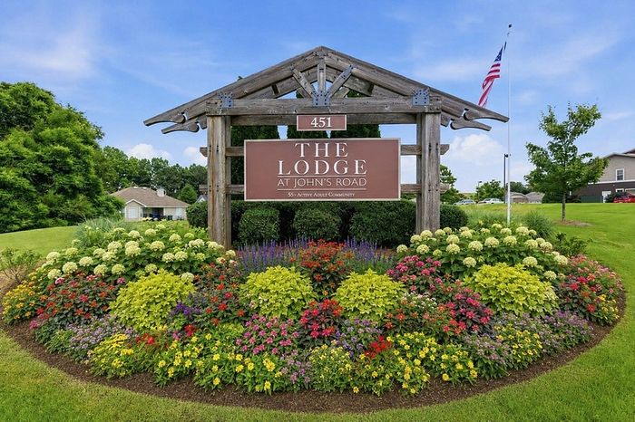 Welcoming entrance of The Lodge at John's Road, surrounded by lush, colorful gardens and vibrant greenery.
