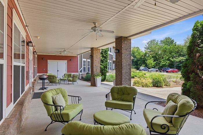 Charming outdoor patio featuring stylish green cushioned chairs, perfect for relaxing in a serene garden setting.