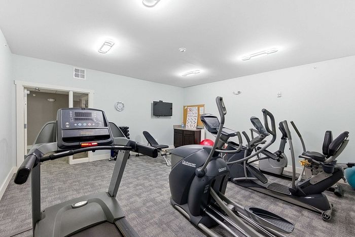 Bright and modern fitness room equipped with treadmills, ellipticals, and exercise bikes, ideal for a convenient workout experience at home.