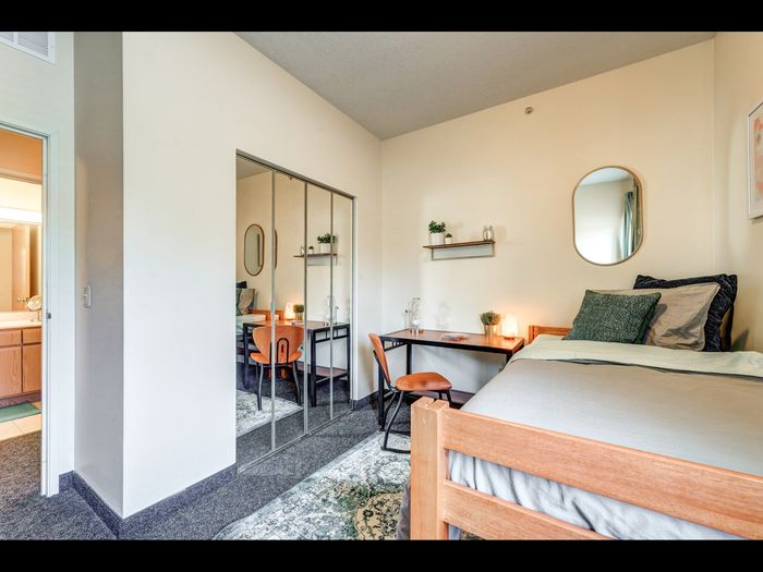 Bedroom with desk and mirrored closet doors in apartment at University Gate | Erie, PA Apartments.