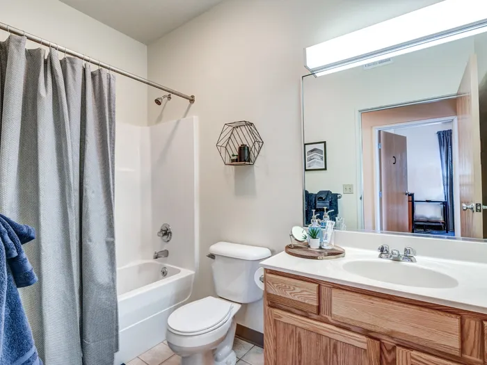 Modern bathroom with large mirror above vanity in apartment at University Gate | Erie, PA Apartments.
