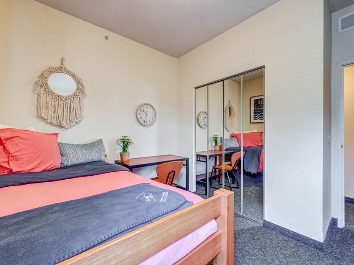 Bedroom with desk and closet with mirrored sliding doors in apartment at University Gate | Erie, PA Apartments.