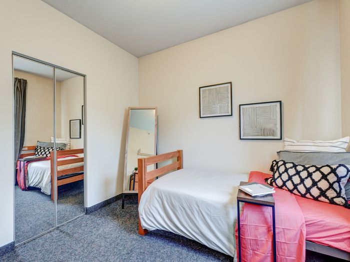 Bedroom with furniture and mirrored sliding doors on closet in apartment at University Gate | Erie, PA Apartments.