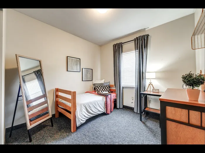 Carpeted bedroom with furnishings in apartment at University Gate | Erie, PA Apartments.