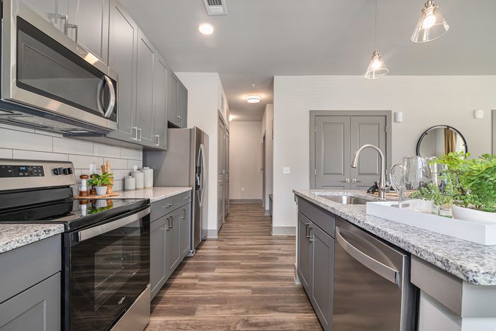 Three-Bedroom Apartments in Birmingham, AL - Tributary Rise - Culinary-Inspired Kitchen With Hardwood-Style Flooring, Granite Countertops, Stainless-Steel Appliances, Designer Lighting, Grey Cabinetry, And Island With Sink.
