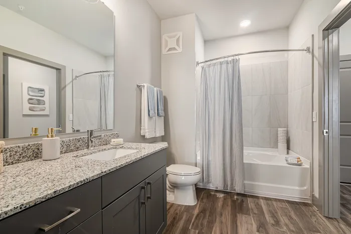 furnished bathroom with shower tub, toilet and sink in apartment home