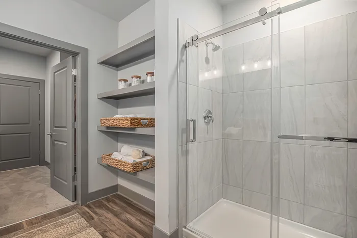 furnished standing shower and shelving in bathroom in apartment home