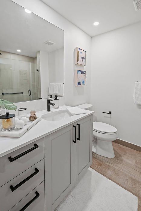 55 Plus Living In Cooper City, FL - Bathroom Has Glass Enclosed Showers, European Cabinetry, Large Mirror, Toilet, And Hard-Wood Flooring.