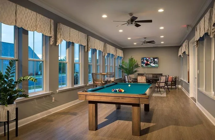 Dog-Friendly Luxury Apartments in Myrtle Beach, SC - Isle Cottages - Game Room With Pool Table, Large Windows, Ceiling Fans, Modern Lighting, and Lounge Seating With Wall-Mounted Television.