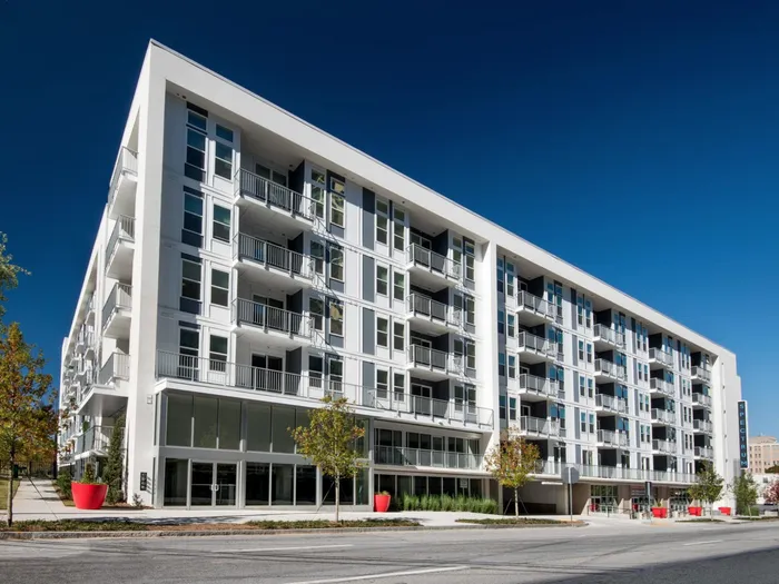 Atlanta, GA, Luxury Apartments for Rent - Spectrum on Spring - Daytime Street View of Property Exterior with White Walls, Trees, and Red Plant Boxes
