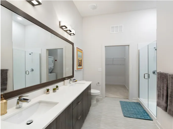 Luxury Apartments In Atlanta, GA For Rent - Spectrum on Spring - Bathroom With Wood-Plank Style Flooring, A Walk-In Closet, Large Vanity Mirror, Dual Sink, Toilet, And Walk-In Shower With Glass Doors.