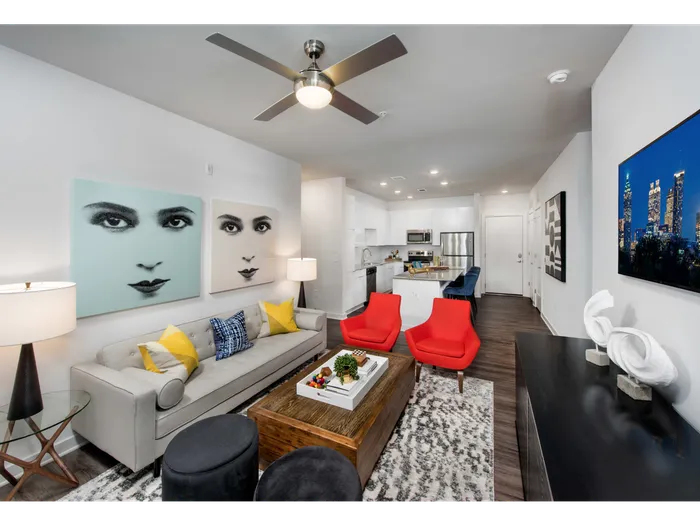Pet-Friendly Apartments In Atlanta, GA - Spectrum on Spring - Open-Floor Living Room With Wood-Style Plank Flooring, High Ceiling, Ceiling Fan, And Access To The Kitchen Area.