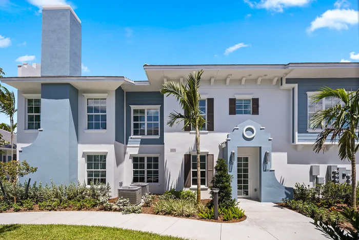 Pet-Friendly Apartments in Lantana, FL - Manor Lantana - Blue and White Building Office Exterior, with Lush Landscaping, Palm Trees, and Manicured Lawn
