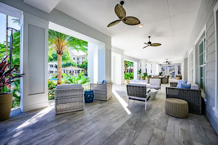 Dog-Friendly Apartments in Lantana, FL - Manor Lantana - Outdoor Patio with Patio Furniture, Ceiling Fans, and Pool View