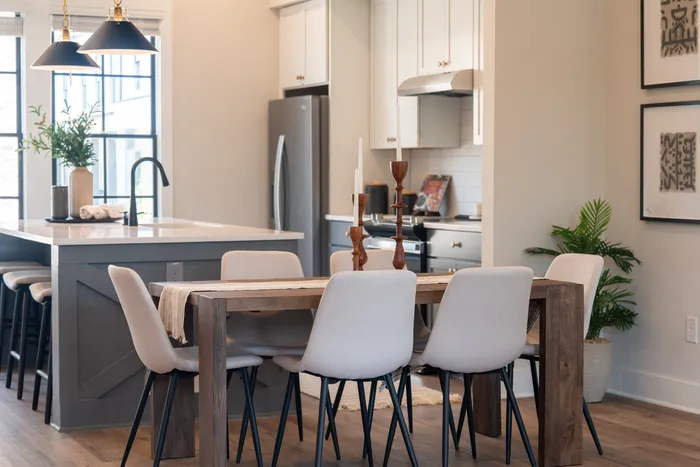 Furnished dining room with table and chairs in front of furnished kitchen