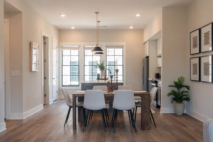 Furnished dining room with table and chairs in front of furnished kitchen