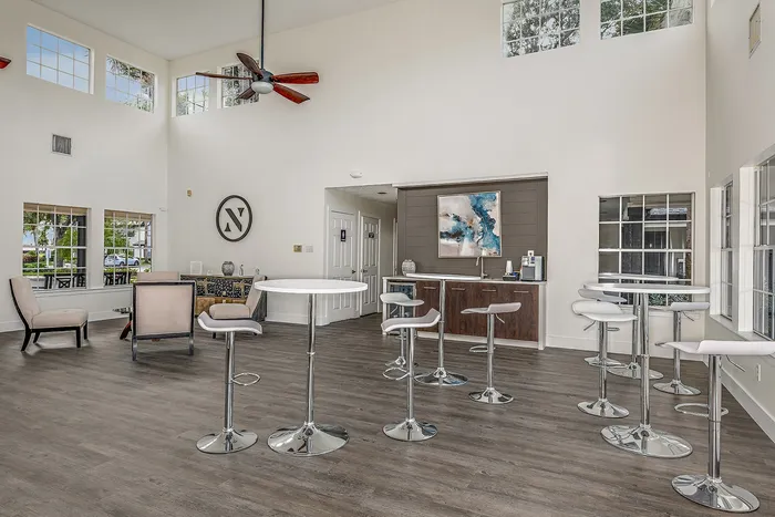 Apartments For Rent in West Melbourne, FL - Caribbean Isle - Clubhouse With Fan, Vaulted Ceilings, High Top Tables With Chairs, Large Windows, And Coffee Bar.
