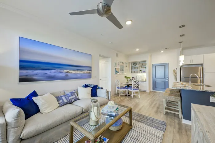 furnished living area with sofa and dining and kitchen area in background in apartment