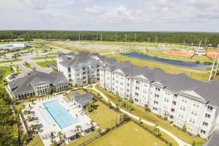 aerial view of apartment building with pool and lake in daytime