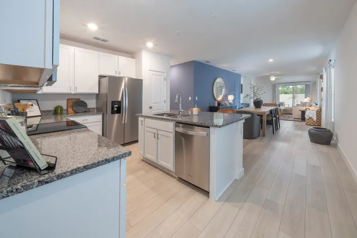 View of the kitchen with stainless steel appliances with view of the furnished dining and living room