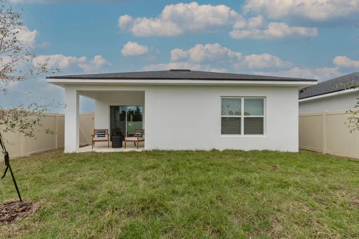 View of the back of the home with covered patio and backyard.