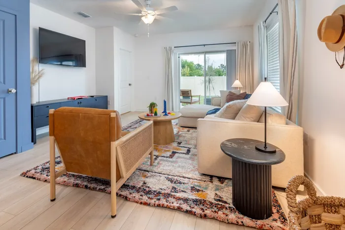 Furnished living room with couch, TV, sitting chair and lighted ceiling fan with view of the outdoor patio