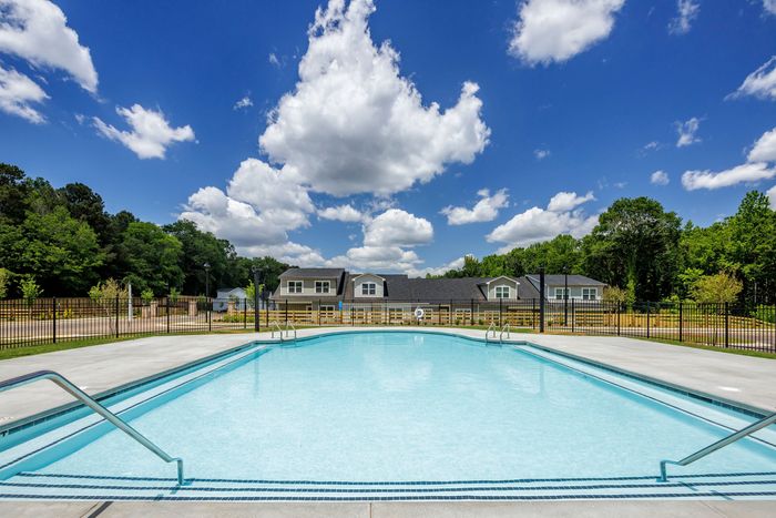 Dog-Friendly Apartments in Loganville, GA - Cottages at Loganville - Pool in Fenced Area, View of Community, and Blue Skies