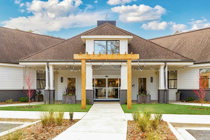 View of exterior of leasing office with green grass in the daytime