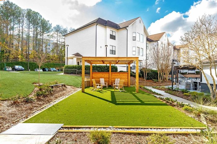 View of the community with greenspace and a gazeebo with seating in the day time