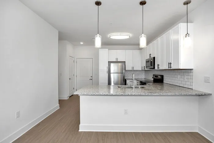 Athens, AL, Apartments Near Huntsville - Gateway Village at Swan Creek - Open-Concept Kitchen With Granite Island, Pendant Lights, Cabinets, Stainless Steel Appliances, and Subway-Tile Backsplash.