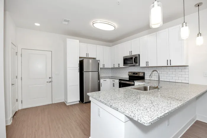 Dog-Friendly Apartments in Athens, AL - Gateway Village - Spacious Modern Kitchen with Stainless Steel Appliances, White Tile Backsplash, White Cabinetry, and Granite Countertops with Expansive Cooking Space