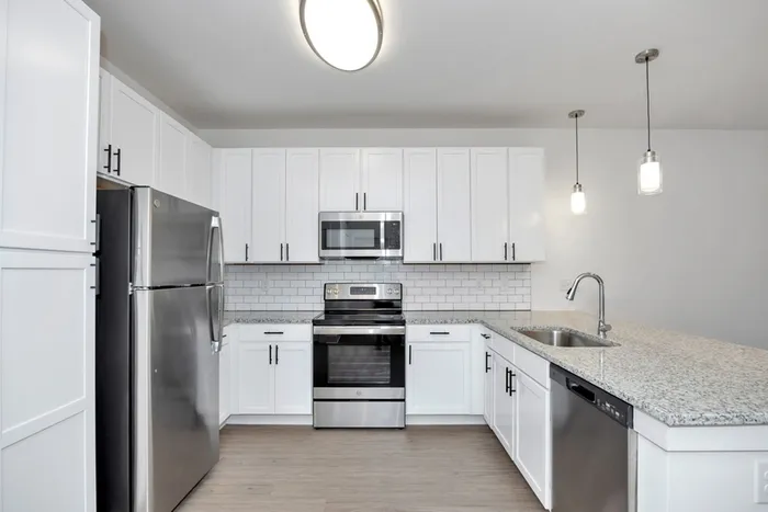 Athens, AL, Luxury Apartments - Gateway Village at Swan Creek - Bright White Kitchen With Granite Countertops, Subway-Tile Backsplash, Pendant Lighting, and Stainless Steel Appliances.
