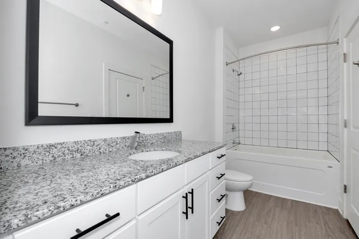 Apartments near Madison, AL - Gateway Village - Bathroom with a Large Mirror, Granite Countertop, Recessed Lighting, Spacious Shower and Tub Combo, and Luxury Wood-Look Flooring.