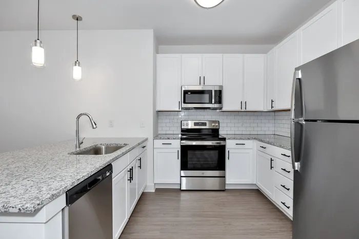 Apartments Near Huntsville, AL - Gateway Village - Kitchen with Stainless Steel Appliances, Granite Countertops, Luxury Wood-Look Flooring, and White Cabinets.
