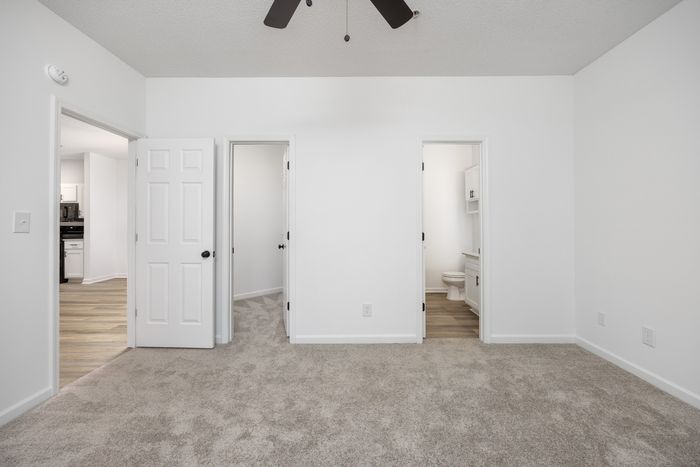unfurnished bedroom with view of common area, bathroom and closet