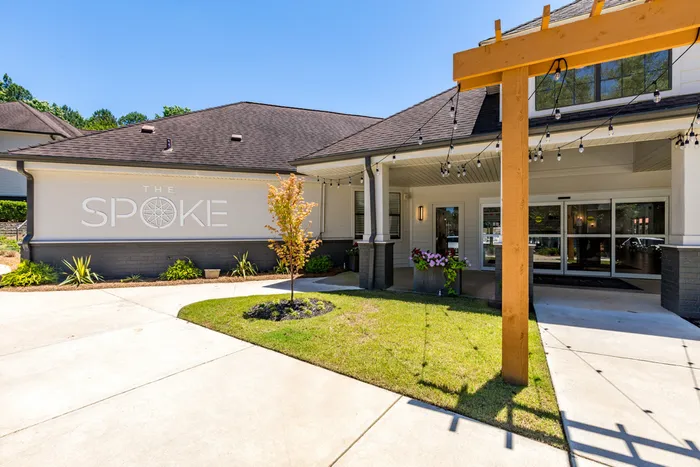 exterior apartment building with pergola and string lights and apartment name sign