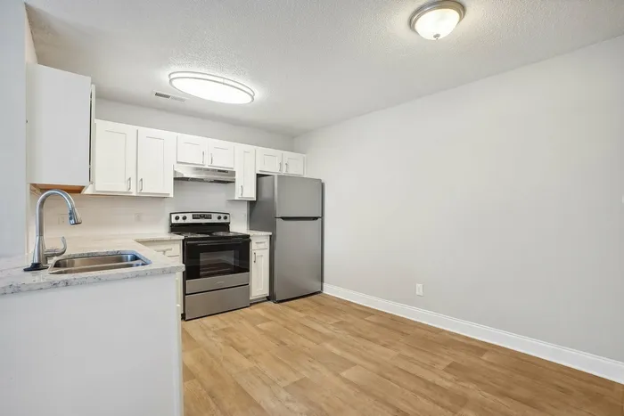 Kitchen with luxury plank flooring and white cabinets and stainless steel appliances