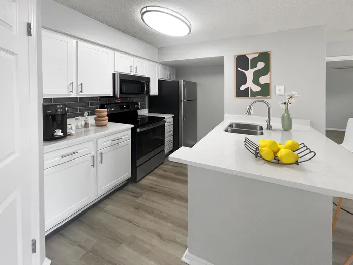Suntree, FL Apartments - Caribbean Isle - Kitchen with an Island, White Cabinets, and a Modern Style Light Fixture