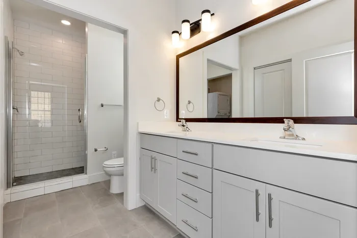 bathroom with dual vanity and walk in shower with tile