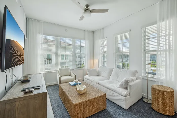 Furnished livingroom with couch, coffee table and lighted ceiling fan