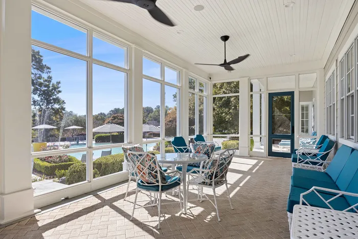 Community sunroom with sitting area and view of the pool