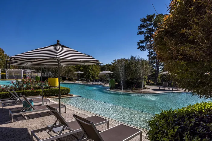 Outdoor pool on a sunny day with pool chairs and umbrella