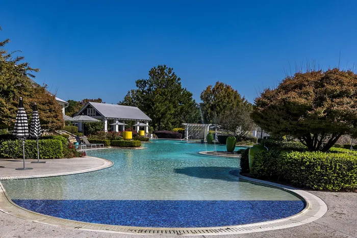 Outdoor pool on a sunny day with pool chairs and umbrella